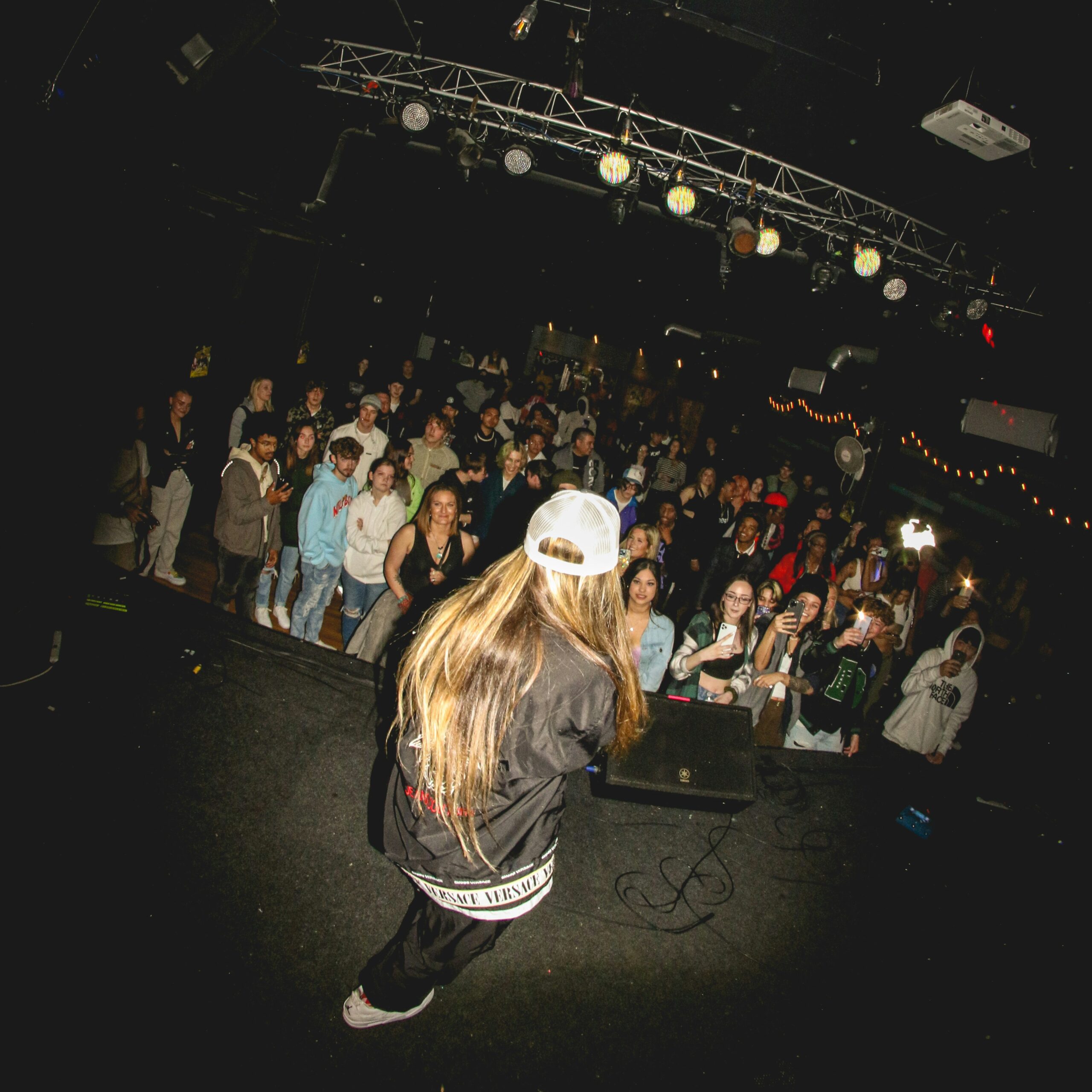 a woman in a white hat is dancing in front of a crowd